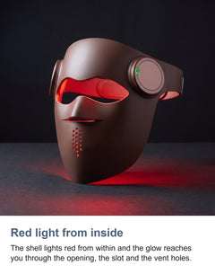 The brown LED face mask lit red in a dark room
