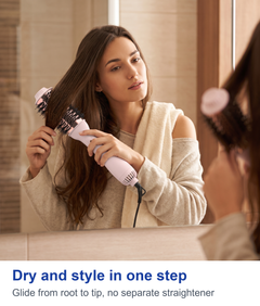 Woman styling her hair with the pink hot air brush at a bathroom mirror
