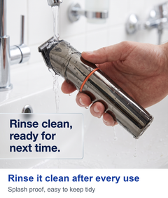 Hand rinsing the trimmer under running water at a bathroom sink