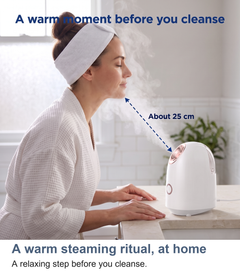 Woman using the facial steamer a short distance from her face