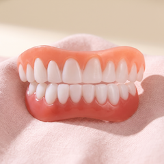 Upper and lower snap on cosmetic teeth veneers resting on soft pink fabric