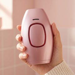Pink handheld IPL hair removal device held in one hand