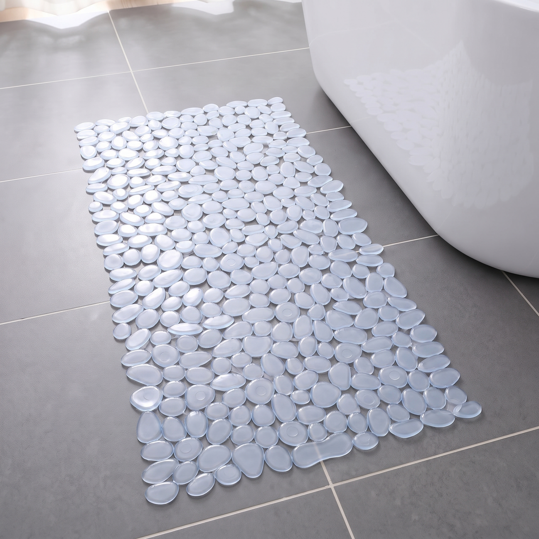Clear pebble shower mat on a grey tiled bathroom floor beside a bath