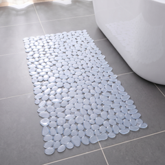 Clear pebble shower mat on a grey tiled bathroom floor beside a bath