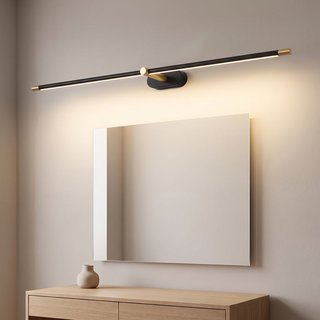 Slim black wired LED over mirror light with brass end caps glowing warm above a mirror