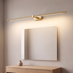 Slim gold wired LED over mirror light glowing warm above a mirror