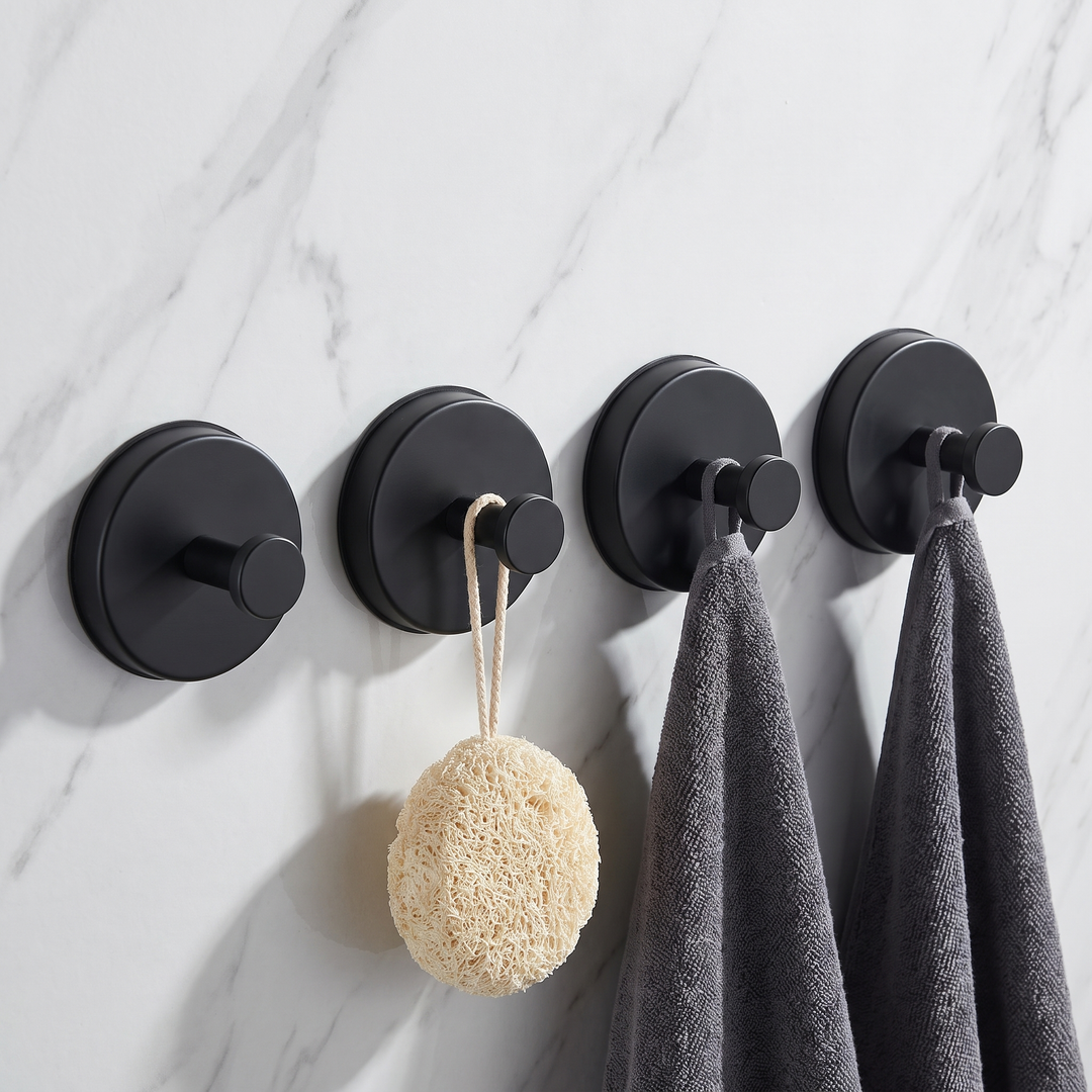 Matte black round suction hooks, pack of four, holding towels and a loofah on a marble wall