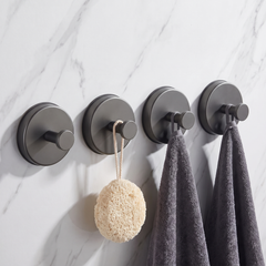 Dark grey round suction hooks, pack of four, holding towels and a loofah on a marble wall