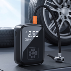 Cordless digital tyre inflator with braided hose beside a car wheel