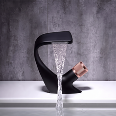 Matt Black and Rose Gold curved waterfall basin mixer tap pouring a flat sheet of water
