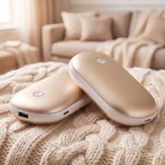 Pack of 2 gold rechargeable pebble hand warmers on a cream cable knit blanket