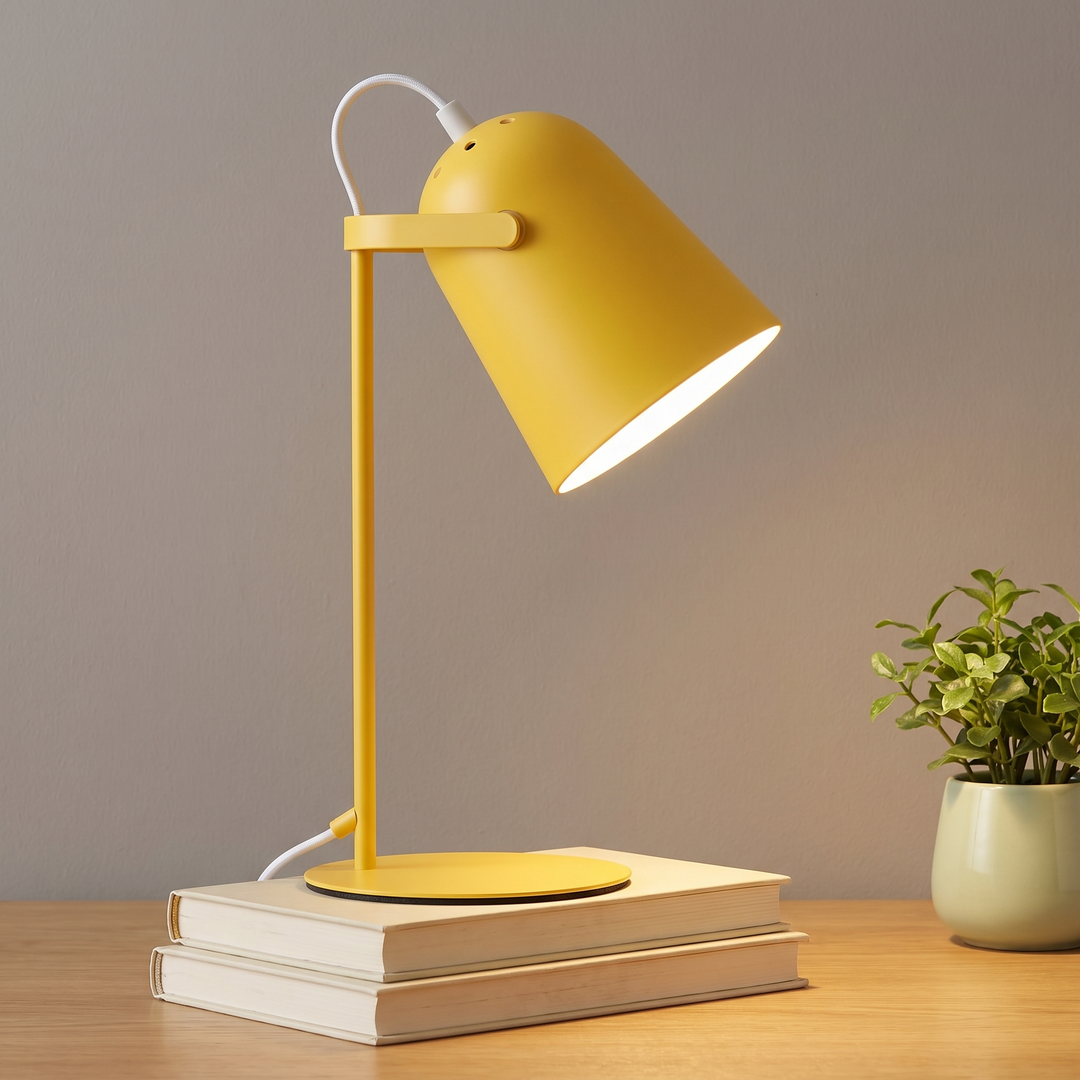 Yellow adjustable metal desk lamp lit on a desk
