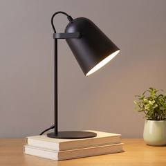 Black adjustable metal desk lamp lit on a desk