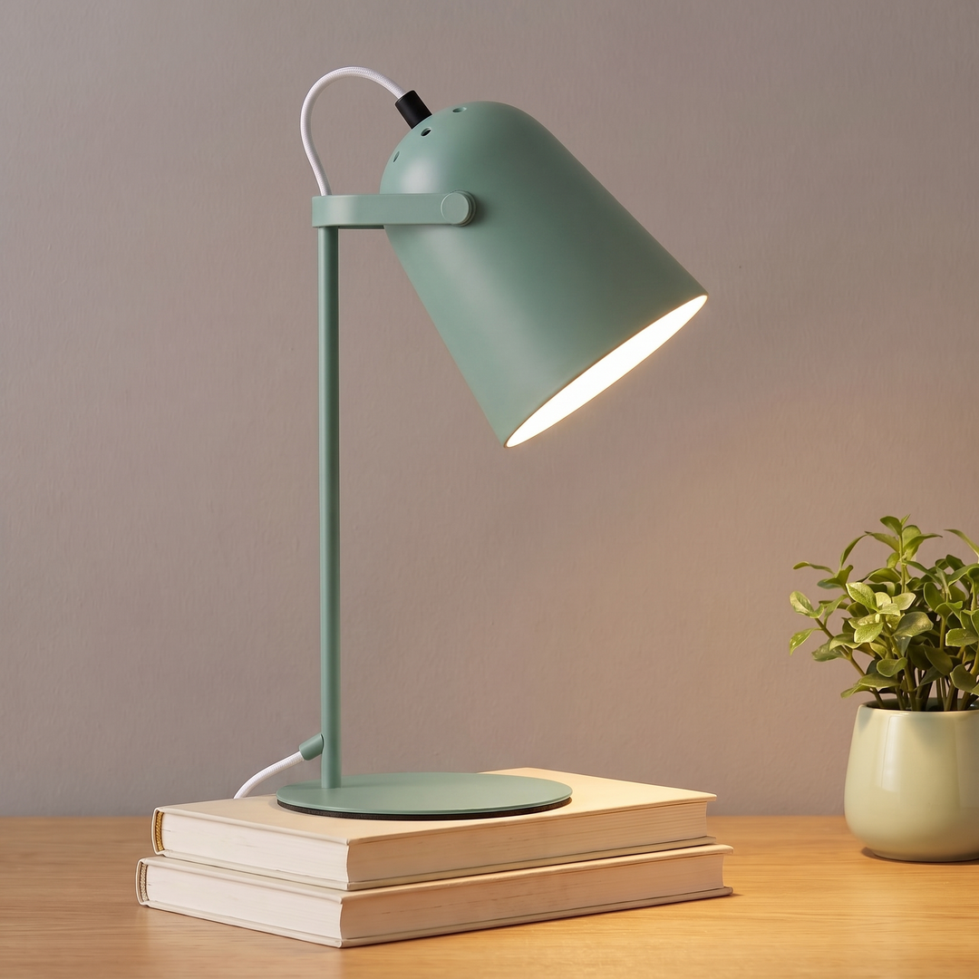 Green adjustable metal desk lamp lit on a desk