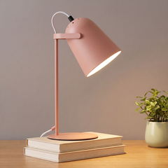 Rose adjustable metal desk lamp lit on a desk