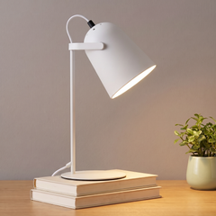 White adjustable metal desk lamp lit on a desk