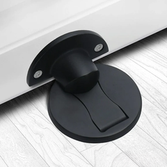 Matte Black magnetic stainless steel door stop on an oak floor at the bottom of an open door
