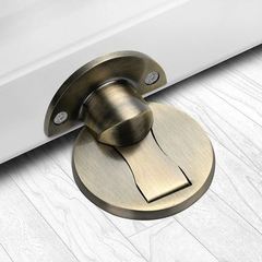 Bronze magnetic stainless steel door stop on an oak floor at the bottom of an open door