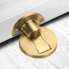 Bright Gold magnetic stainless steel door stop on an oak floor at the bottom of an open door