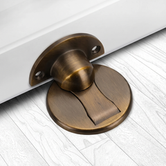 Yellow Bronze magnetic stainless steel door stop on an oak floor at the bottom of an open door