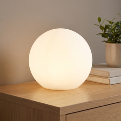 Rechargeable LED globe lamp glowing warm white on a wooden console