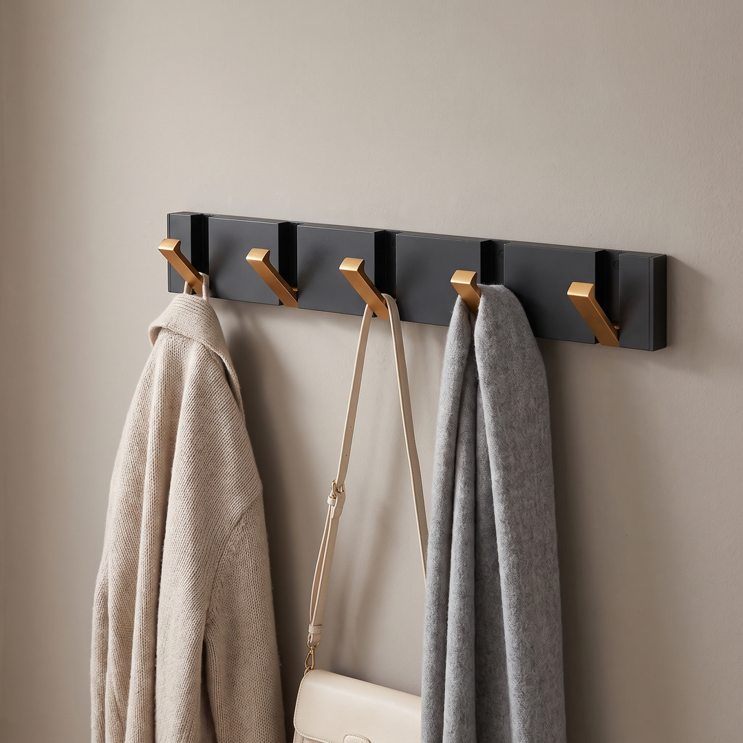 Folding wall hook rail with black rail and gold hooks holding coats in a hallway