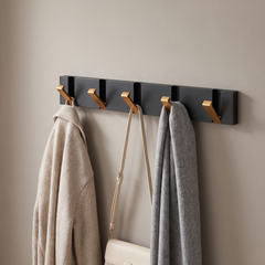 Folding wall hook rail with black rail and gold hooks holding coats in a hallway