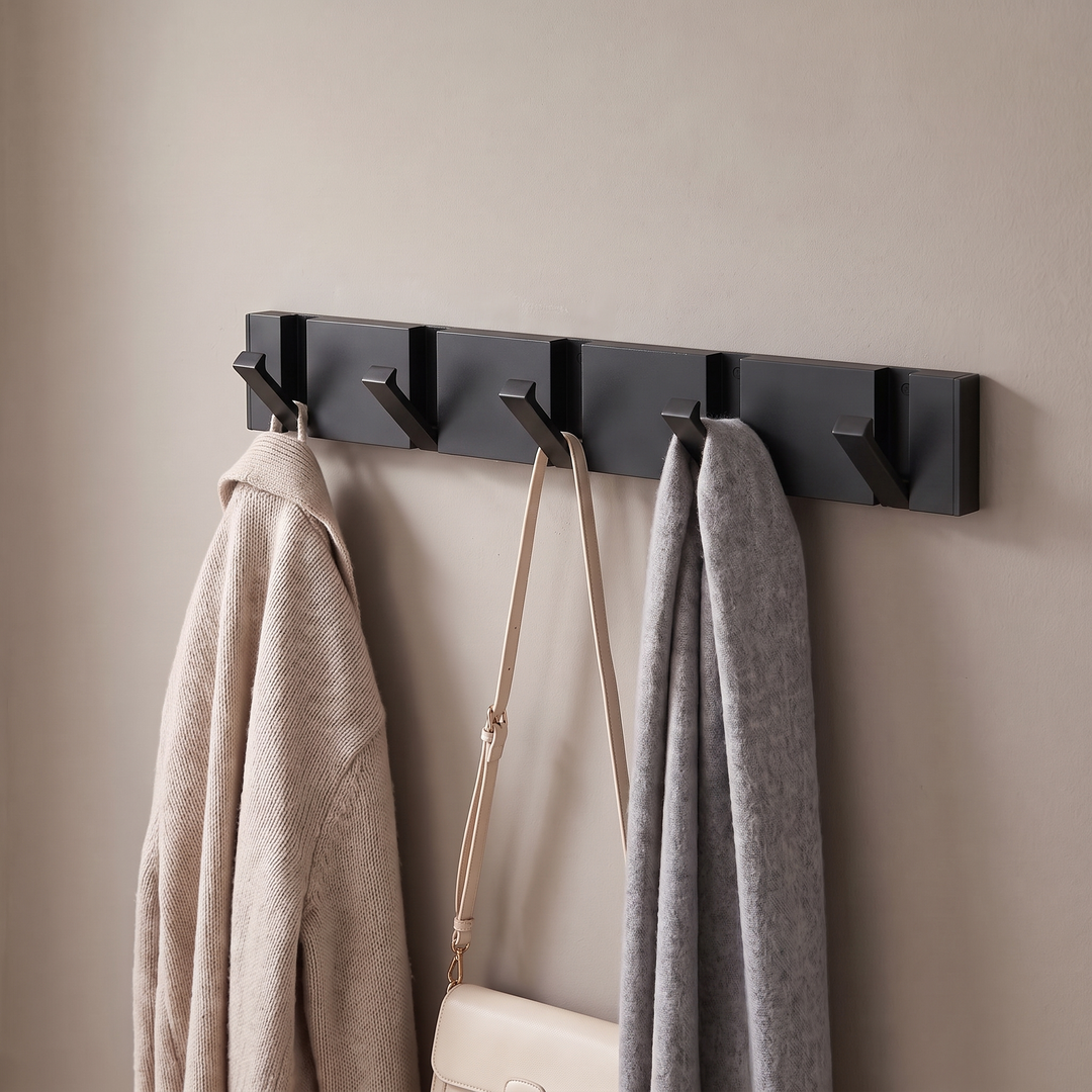 Black folding wall hook rail with black hooks holding coats in a hallway