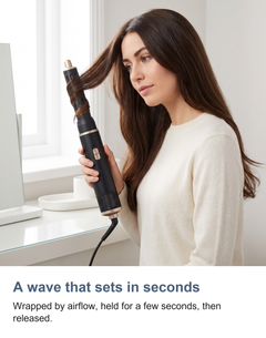 The 5 in 1 air curler used at a dressing table, a section wrapped around the curling barrel