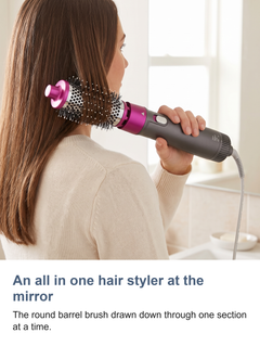 The hot air styler brush used at a mirror, drawing the round barrel brush through one section of hair