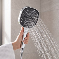Silver handheld high pressure shower head with a black square face, spraying water