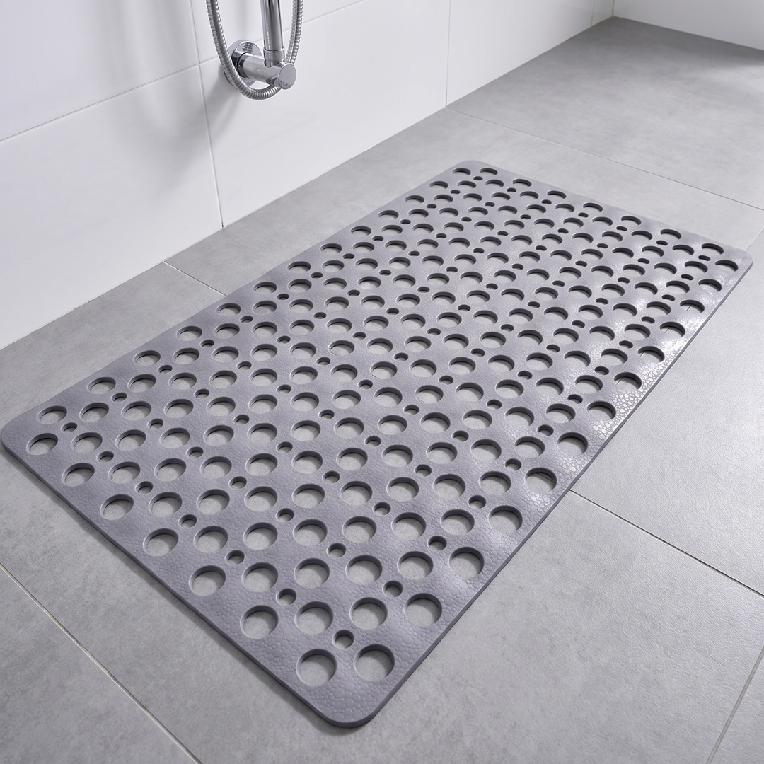 Grey non slip shower mat with suction cups and drainage holes on a shower floor