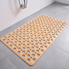 Beige non slip shower mat with suction cups and drainage holes on a shower floor