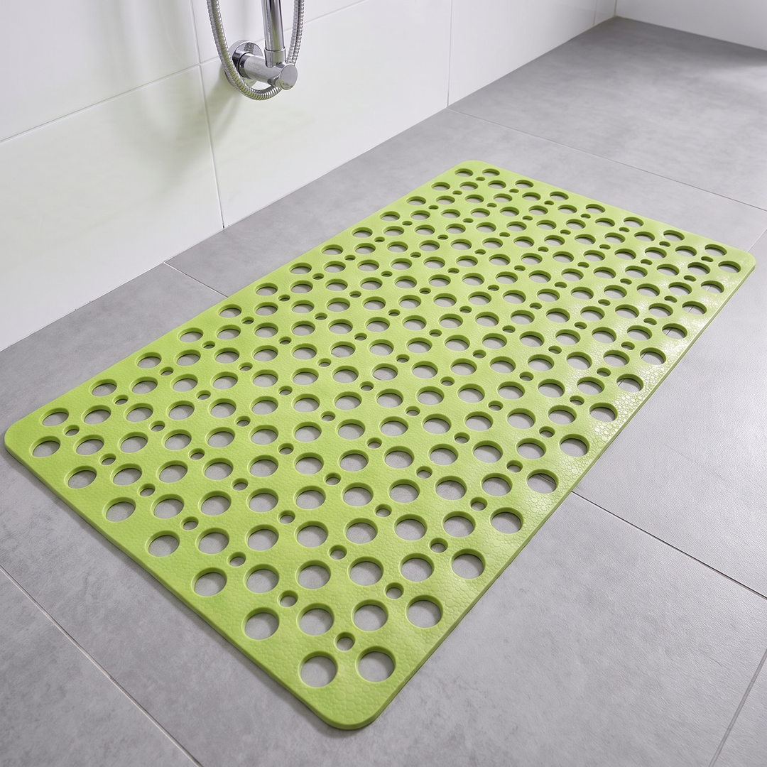 Green non slip shower mat with suction cups and drainage holes on a shower floor