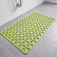 Green non slip shower mat with suction cups and drainage holes on a shower floor