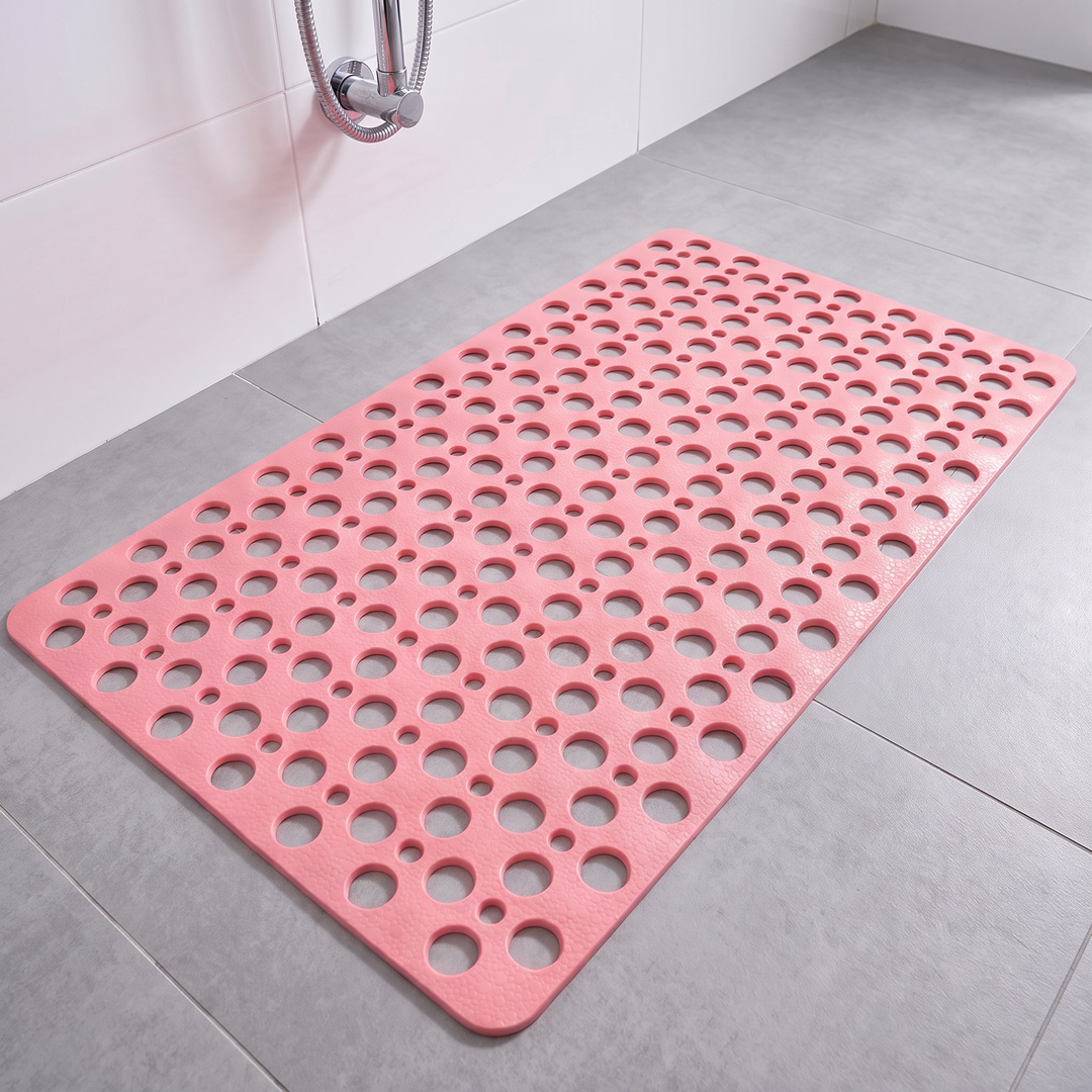 Pink non slip shower mat with suction cups and drainage holes on a shower floor