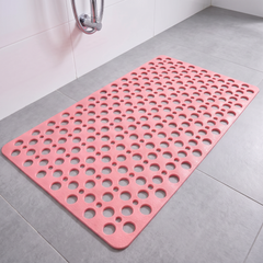 Pink non slip shower mat with suction cups and drainage holes on a shower floor