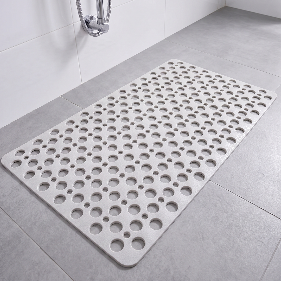 White non slip shower mat with suction cups and drainage holes on a shower floor