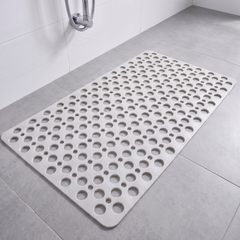 White non slip shower mat with suction cups and drainage holes on a shower floor