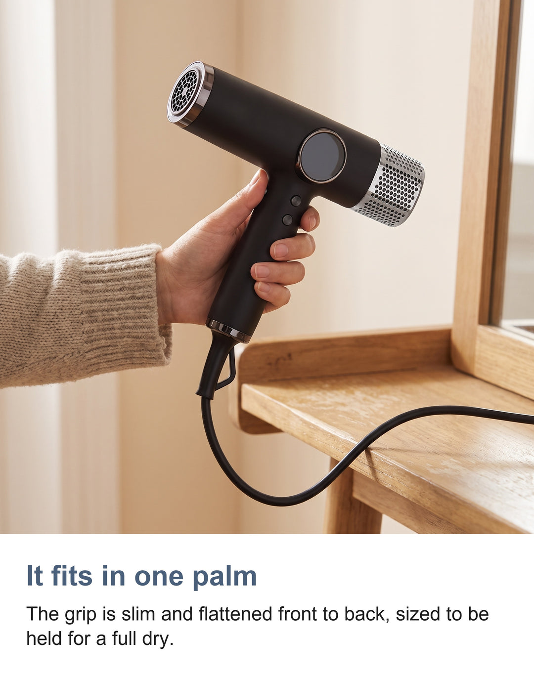 The hair dryer held in one palm to show its size
