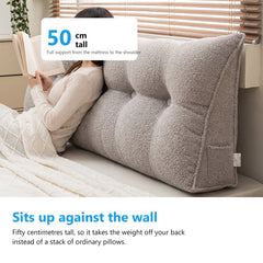 Woman sitting up in bed reading a book against a triangle headboard cushion