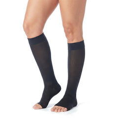 Legs wearing black knee high open toe compression stockings on a white background