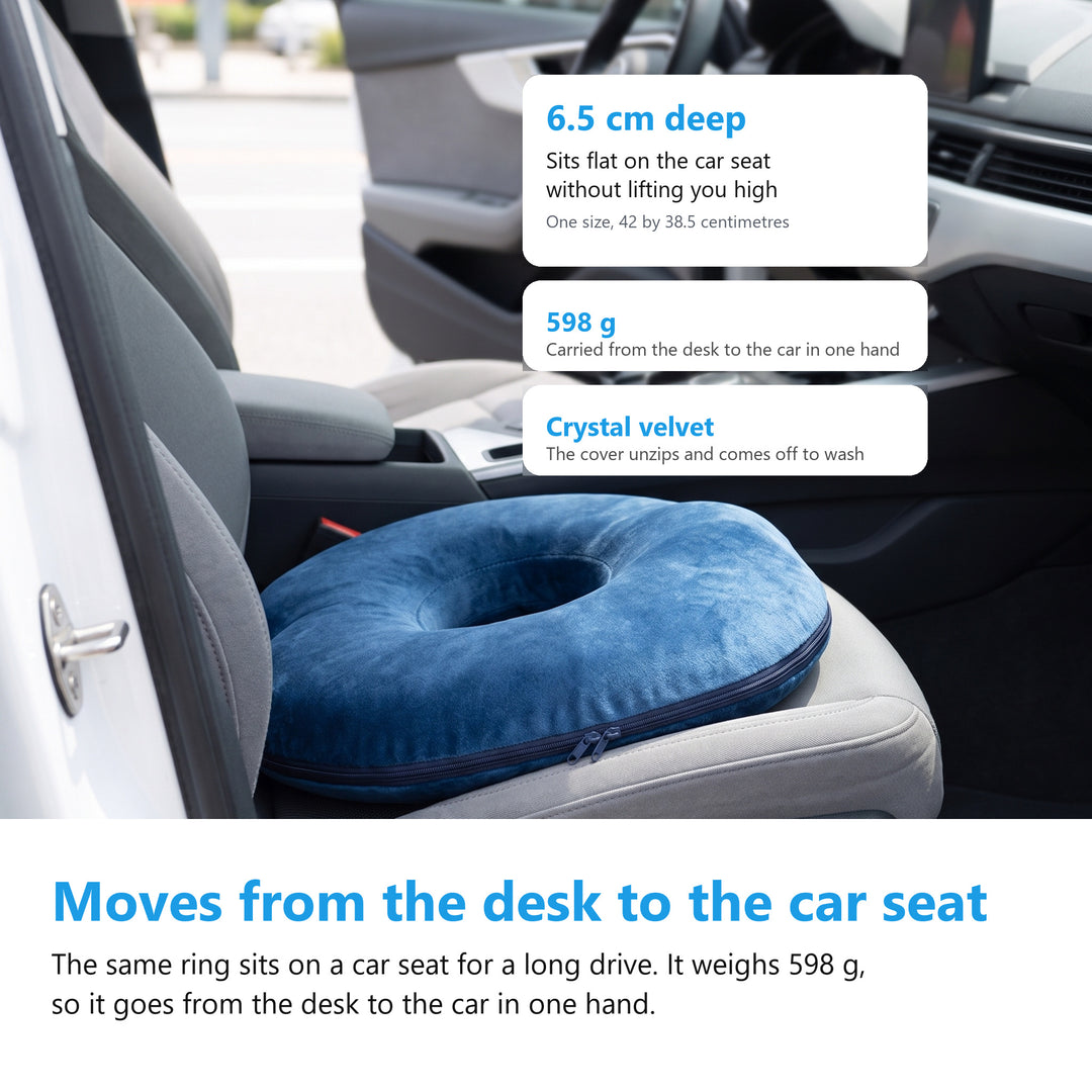 Navy donut cushion sitting on the driver seat of a car with the door open