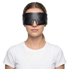 Woman wearing the black 3D contoured silk eye mask on a white background, the wide silk band covering both eyes and temples