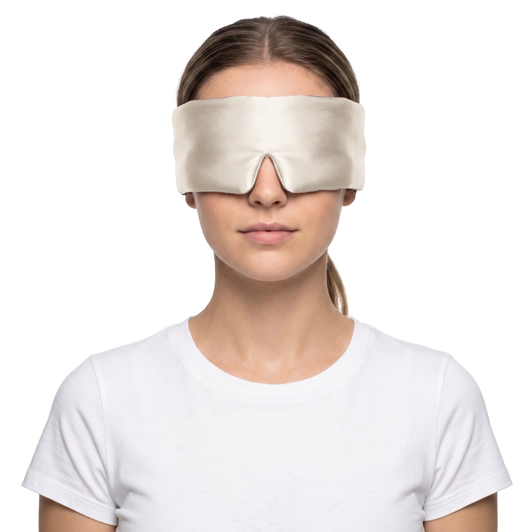 Woman wearing the champagne 3D contoured silk eye mask on a white background, the wide silk band covering both eyes and temples