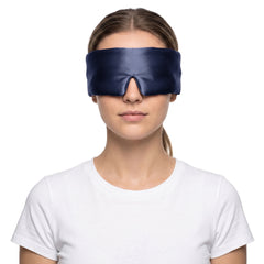 Woman wearing the navy blue 3D contoured silk eye mask on a white background, the wide silk band covering both eyes and temples