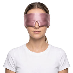 Woman wearing the pink 3D contoured silk eye mask on a white background, the wide silk band covering both eyes and temples