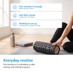 Black textured foam roller on a grey yoga mat in a bright living room with a water bottle and a towel