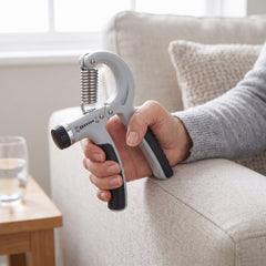 Hand grip strengthener held while sitting back on a sofa