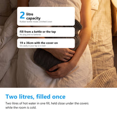 Hot water bottle held close in bed under a duvet at night, two litre capacity